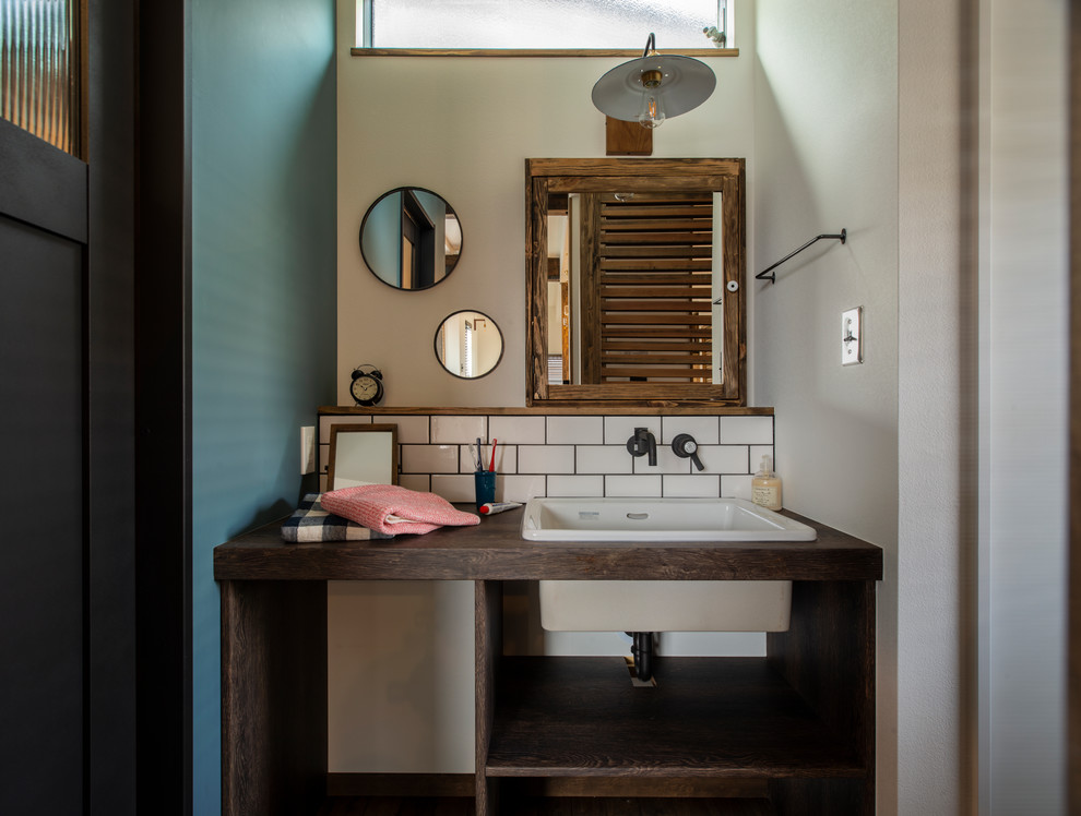 Inspiration for a mid-sized industrial white tile and subway tile powder room remodel in Other with open cabinets, white walls, an integrated sink, laminate countertops and brown countertops