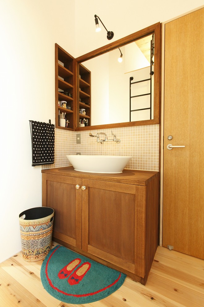 This is an example of a small rural cloakroom in Other with recessed-panel cabinets, distressed cabinets, white walls, light hardwood flooring, a vessel sink, wooden worktops, beige floors and brown worktops.