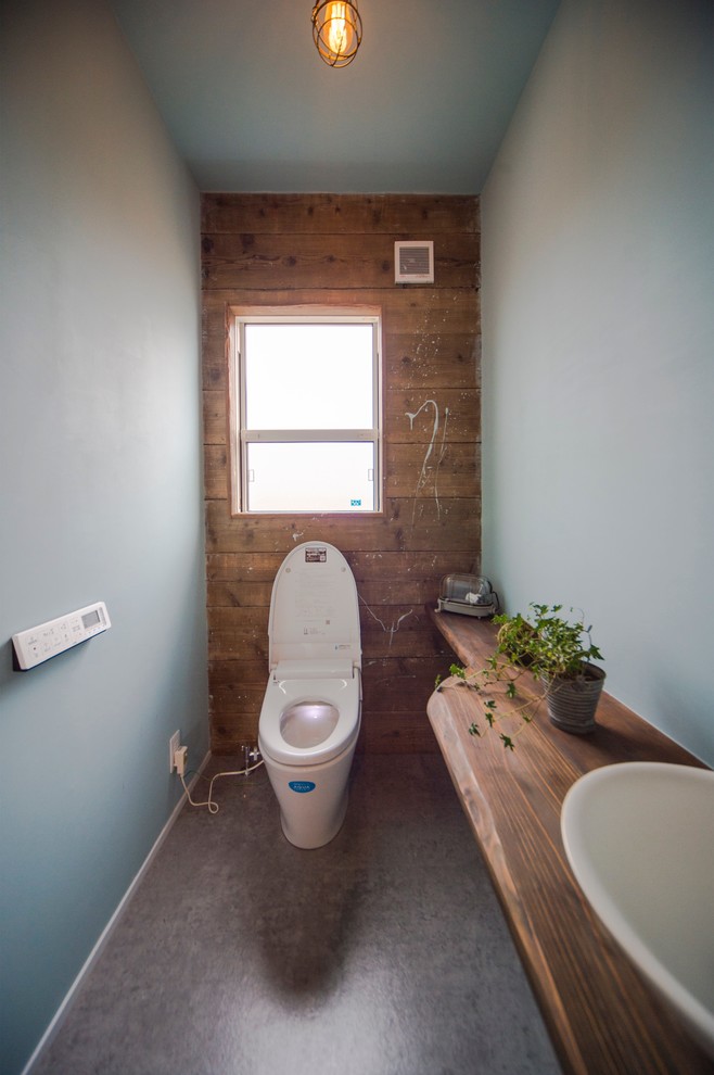 Cette photo montre un grand WC et toilettes bord de mer avec un placard sans porte, des portes de placard marrons, un mur blanc, un sol en vinyl, un lavabo intégré, un plan de toilette en bois, un sol gris et un plan de toilette marron.