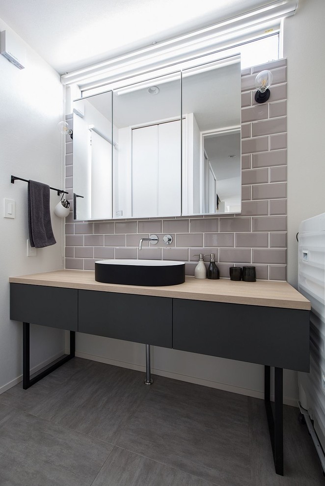Exempel på ett industriellt toalett, med släta luckor, svarta skåp, vita väggar, betonggolv, ett fristående handfat, träbänkskiva och grått golv