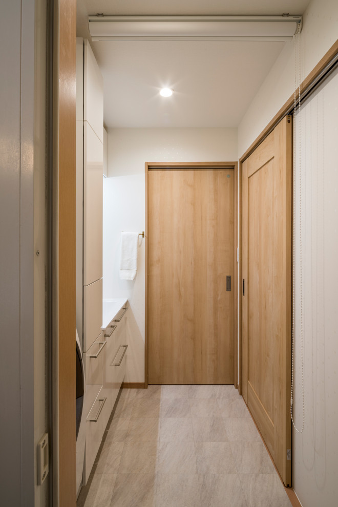 Réalisation d'un WC et toilettes minimaliste de taille moyenne avec des portes de placard blanches, un mur blanc, un lavabo intégré, un sol gris et un plan de toilette blanc.