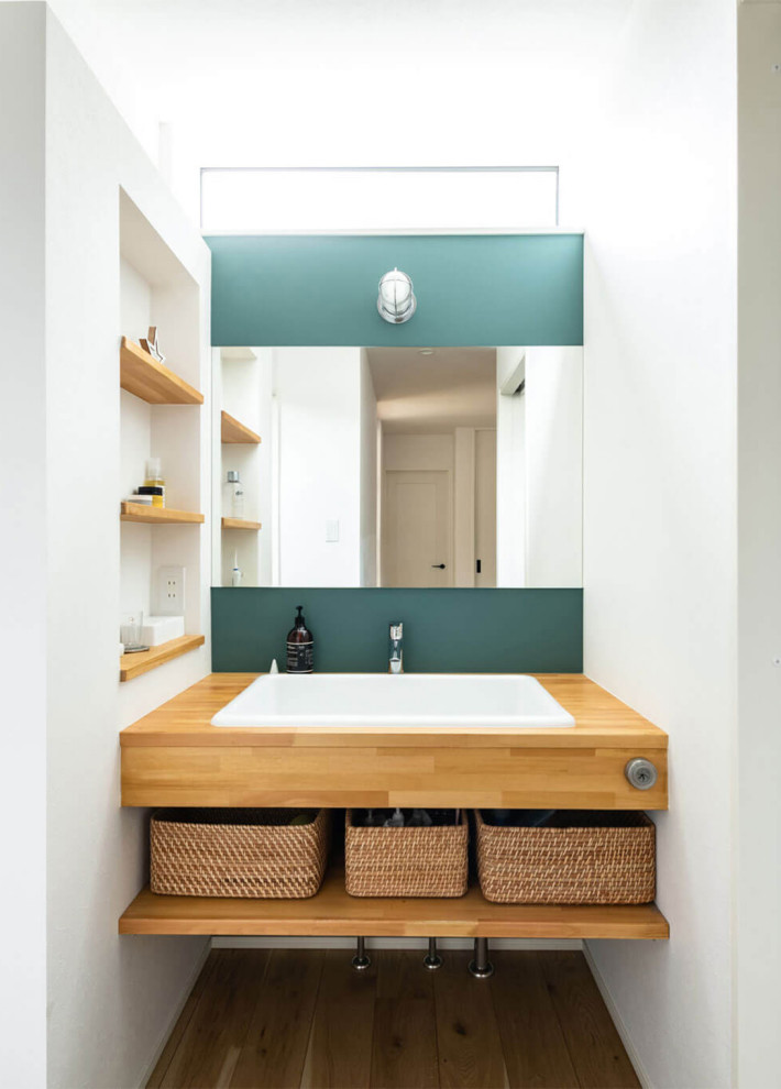 福岡にある北欧スタイルのおしゃれなトイレ・洗面所 (オープンシェルフ、中間色木目調キャビネット、白いタイル、白い壁、白い洗面カウンター) の写真