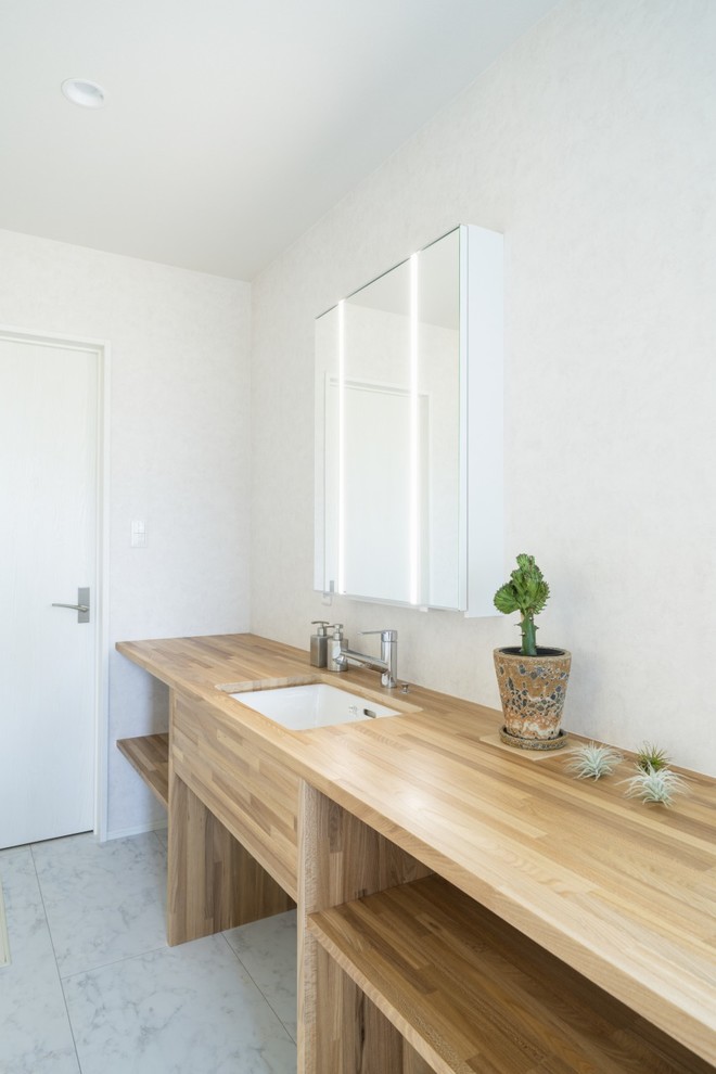 Esempio di un bagno di servizio minimalista di medie dimensioni con consolle stile comò, ante in legno chiaro, pareti bianche, parquet chiaro, lavabo sottopiano, top in superficie solida, pavimento marrone e top beige