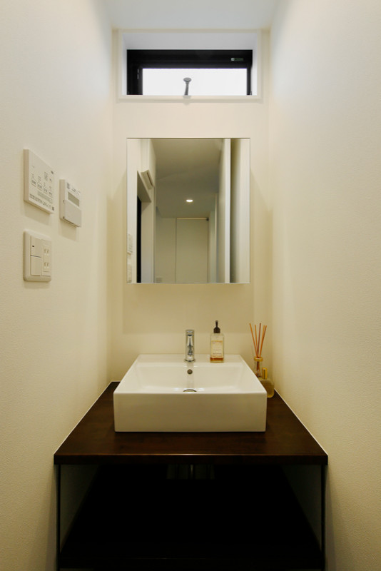 Inspiration för små industriella brunt toaletter, med öppna hyllor, bruna skåp, vita väggar, mörkt trägolv, ett nedsänkt handfat, bänkskiva i akrylsten och brunt golv