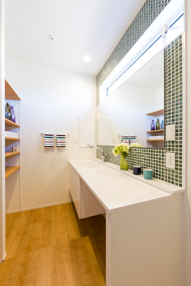 Inspiration pour un WC et toilettes minimaliste en bois brun avec un placard sans porte, un carrelage vert, un mur blanc, un sol en bois brun, un sol marron et un plan de toilette blanc.