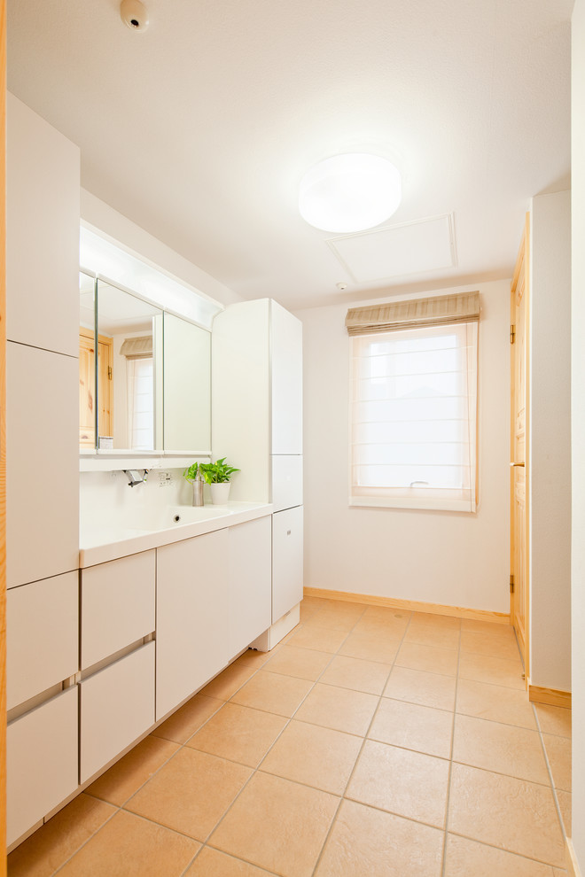 他の地域にある広い北欧スタイルのおしゃれなトイレ・洗面所 (フラットパネル扉のキャビネット、白いキャビネット、白い壁、テラコッタタイルの床、ベージュの床、白い洗面カウンター) の写真