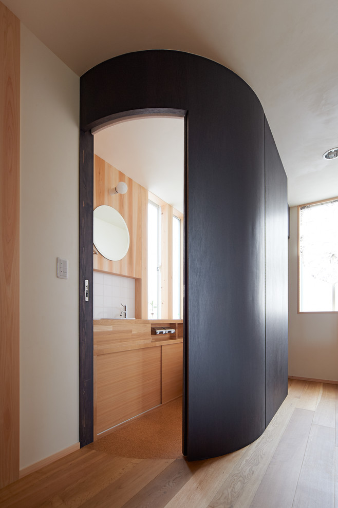 Bild på ett funkis beige beige toalett, med möbel-liknande, korkgolv, träbänkskiva, svarta skåp, vit kakel, porslinskakel, svarta väggar, ett undermonterad handfat och beiget golv