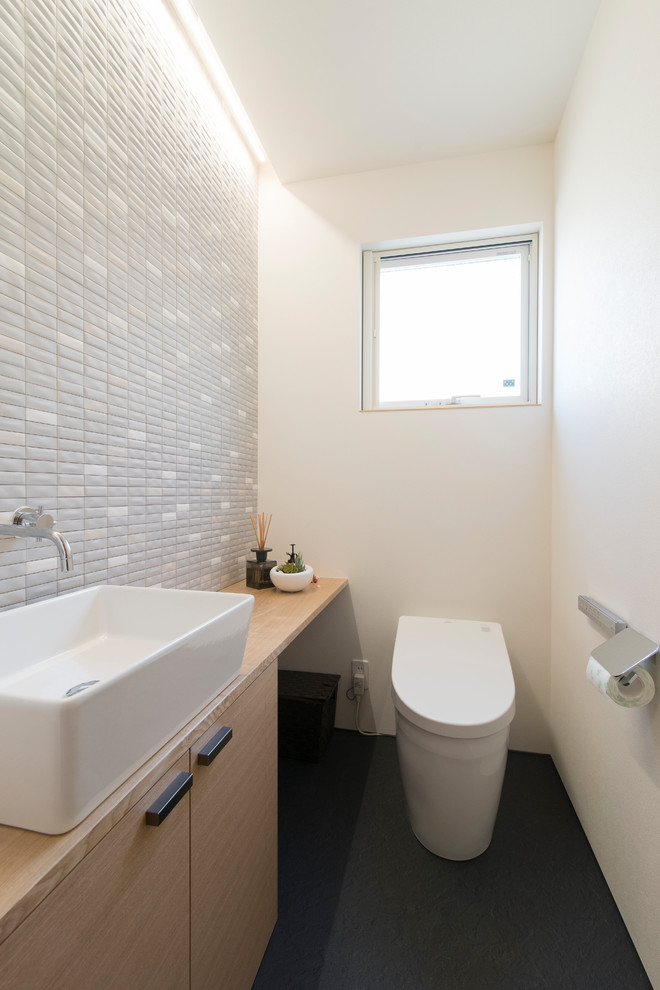 Inspiration for a medium sized modern cloakroom in Other with brown cabinets, a one-piece toilet, grey tiles, white walls, black floors, beaded cabinets, porcelain tiles, a built-in sink, a built in vanity unit, a wallpapered ceiling and wallpapered walls.