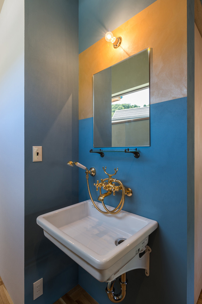 Cette image montre un petit WC et toilettes marin avec un mur bleu et un lavabo suspendu.