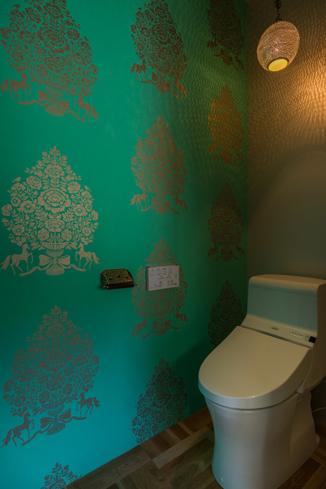 Maritime Gästetoilette mit Toilette mit Aufsatzspülkasten, grüner Wandfarbe und braunem Holzboden in Yokohama