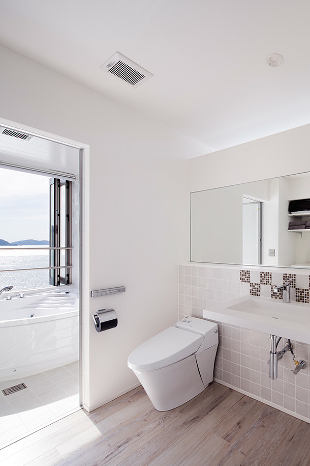 Réalisation d'un WC et toilettes minimaliste avec un carrelage gris, un mur blanc, un lavabo suspendu, parquet clair et un sol beige.