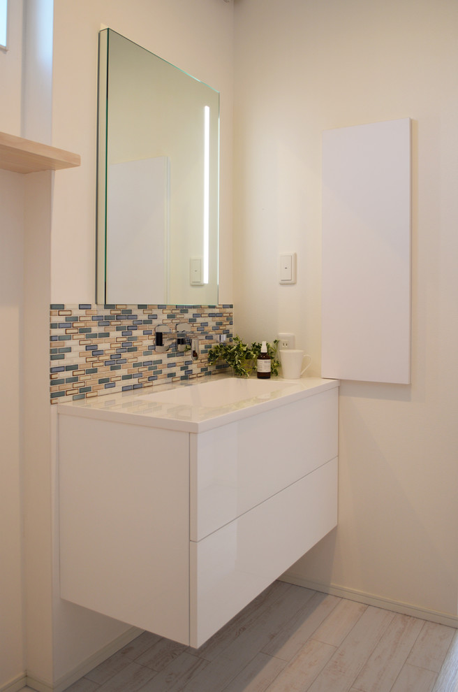 他の地域にある北欧スタイルのおしゃれなトイレ・洗面所 (白いキャビネット、マルチカラーのタイル、モザイクタイル、白い壁、淡色無垢フローリング、グレーの床) の写真