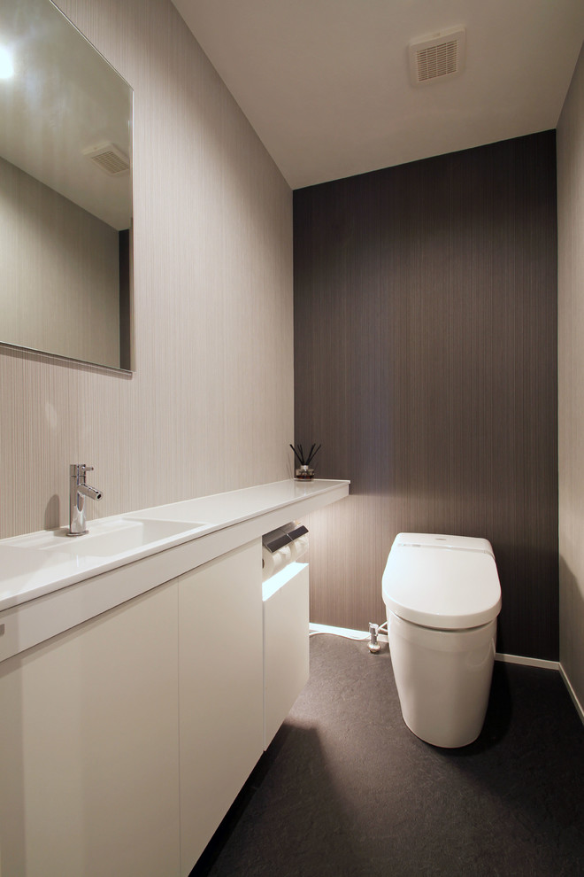 Свежая идея для дизайна: туалет в стиле модернизм с плоскими фасадами, белыми фасадами, серыми стенами, монолитной раковиной, серым полом и белой столешницей - отличное фото интерьера