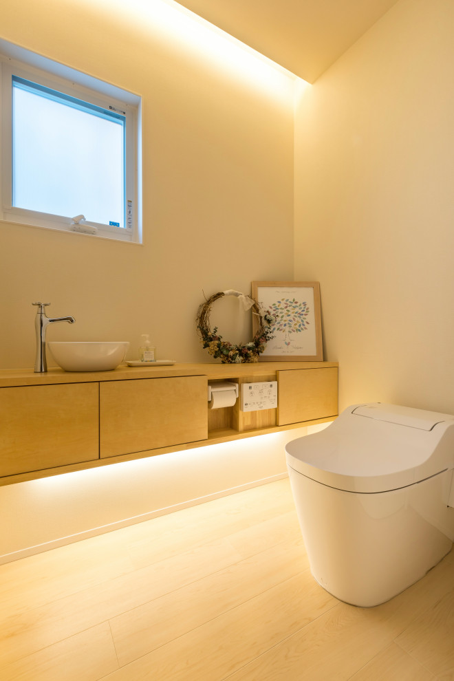 Contemporary cloakroom in Other with beige cabinets, a one-piece toilet, a built-in sink, wooden worktops and beige worktops.