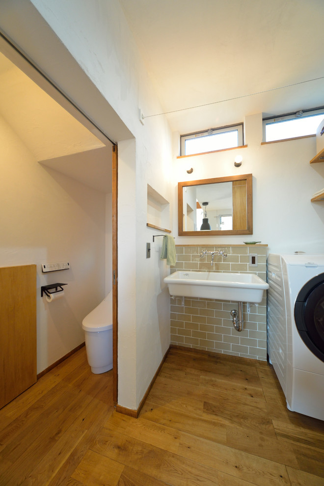 Источник вдохновения для домашнего уюта: туалет в восточном стиле с белыми стенами, паркетным полом среднего тона, консольной раковиной и коричневым полом