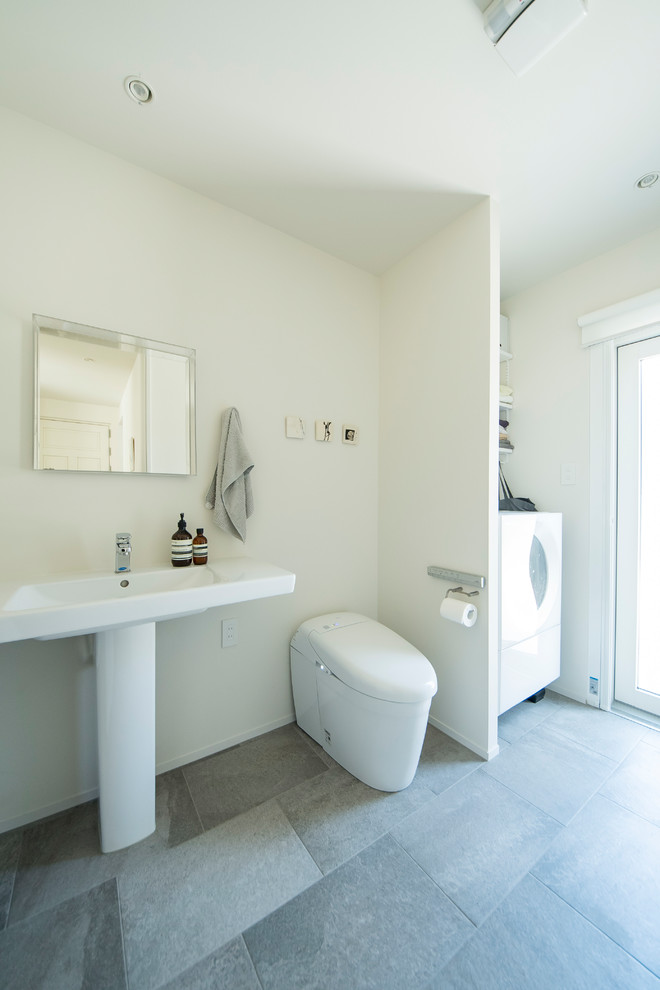 Cette image montre un WC et toilettes nordique avec un mur blanc et un sol gris.