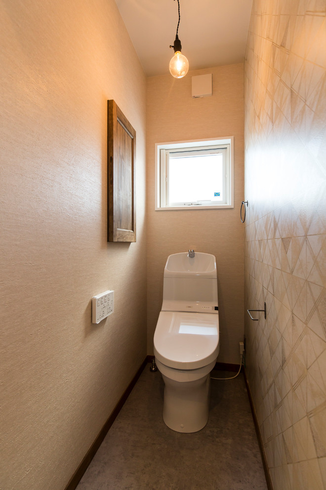Idée de décoration pour un WC et toilettes minimaliste avec un mur beige et un sol gris.