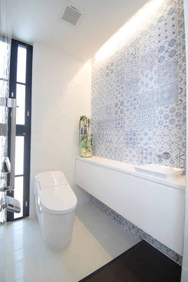 На фото: туалет в стиле модернизм с белыми фасадами, синей плиткой, керамогранитной плиткой, белыми стенами, полом из керамогранита и белым полом