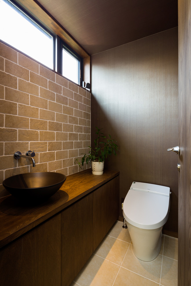 На фото: туалет в стиле ретро с плоскими фасадами, темными деревянными фасадами, серыми стенами, столешницей из дерева, бежевым полом и коричневой столешницей с