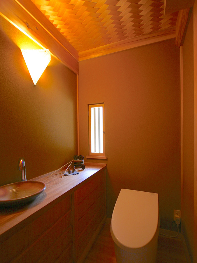 Свежая идея для дизайна: туалет с унитазом-моноблоком, паркетным полом среднего тона и столешницей из дерева - отличное фото интерьера