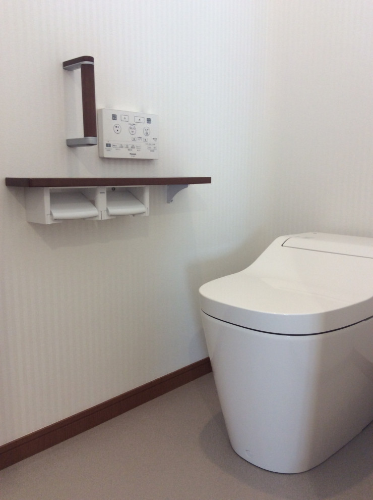 Foto di un piccolo bagno di servizio stile americano con WC monopezzo, pareti bianche, pavimento in laminato, pavimento marrone, soffitto in carta da parati e carta da parati
