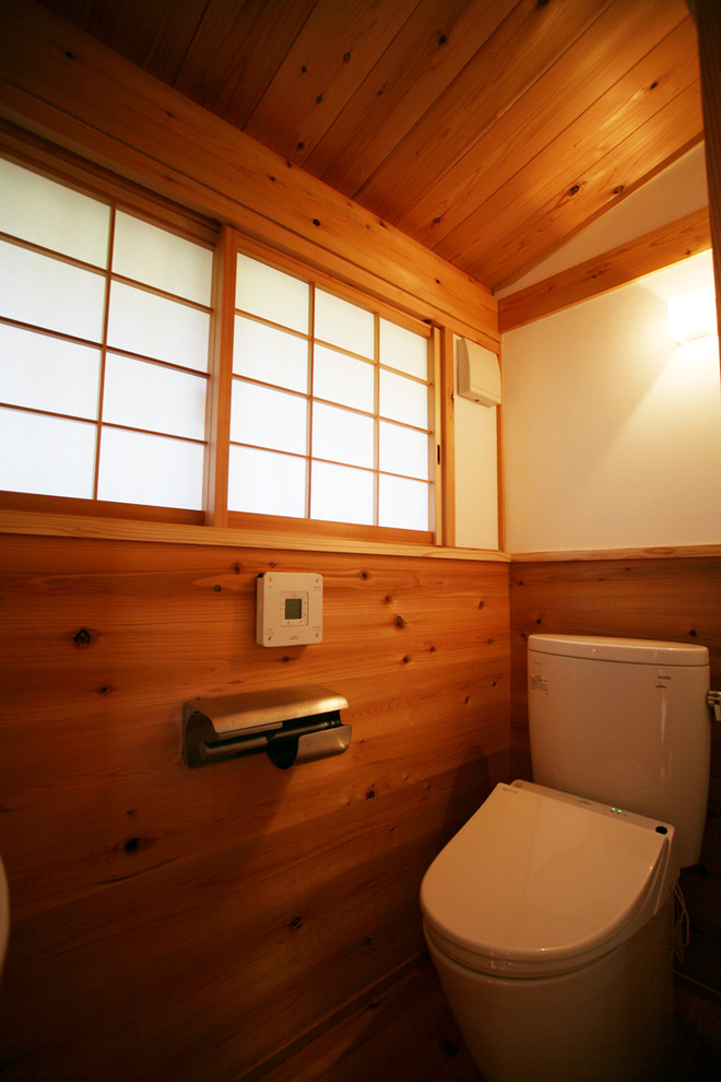 Ejemplo de aseo de estilo zen pequeño con sanitario de pared, paredes blancas, suelo de madera en tonos medios y suelo marrón