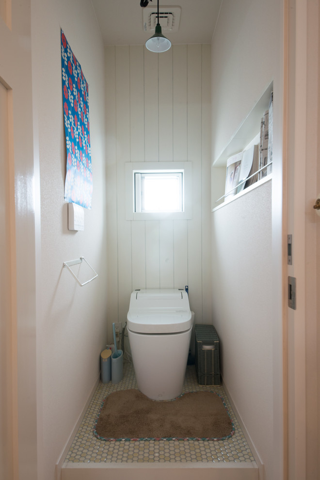 Cette image montre un WC et toilettes nordique avec un mur blanc, carreaux de ciment au sol et un sol vert.