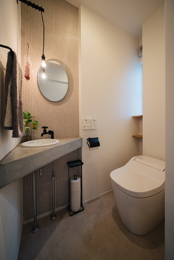 Réalisation d'un WC et toilettes nordique avec un carrelage blanc, des carreaux de porcelaine, un mur blanc, sol en béton ciré, un lavabo posé et un sol gris.
