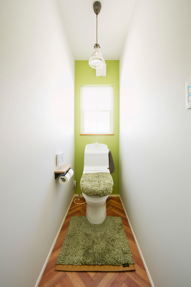 Cette photo montre un WC et toilettes scandinave avec un mur multicolore, un sol en bois brun et un sol marron.