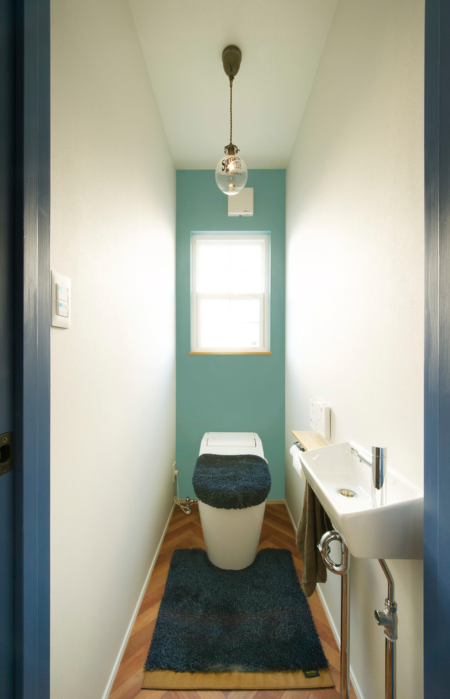 Источник вдохновения для домашнего уюта: туалет в скандинавском стиле с разноцветными стенами, паркетным полом среднего тона, консольной раковиной и коричневым полом