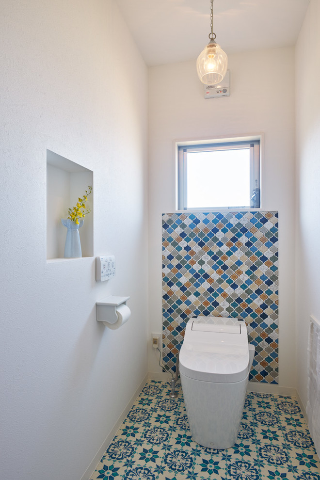 Cette image montre un WC et toilettes méditerranéen avec WC à poser, un carrelage multicolore, un mur blanc, un sol en carrelage de porcelaine et un sol multicolore.