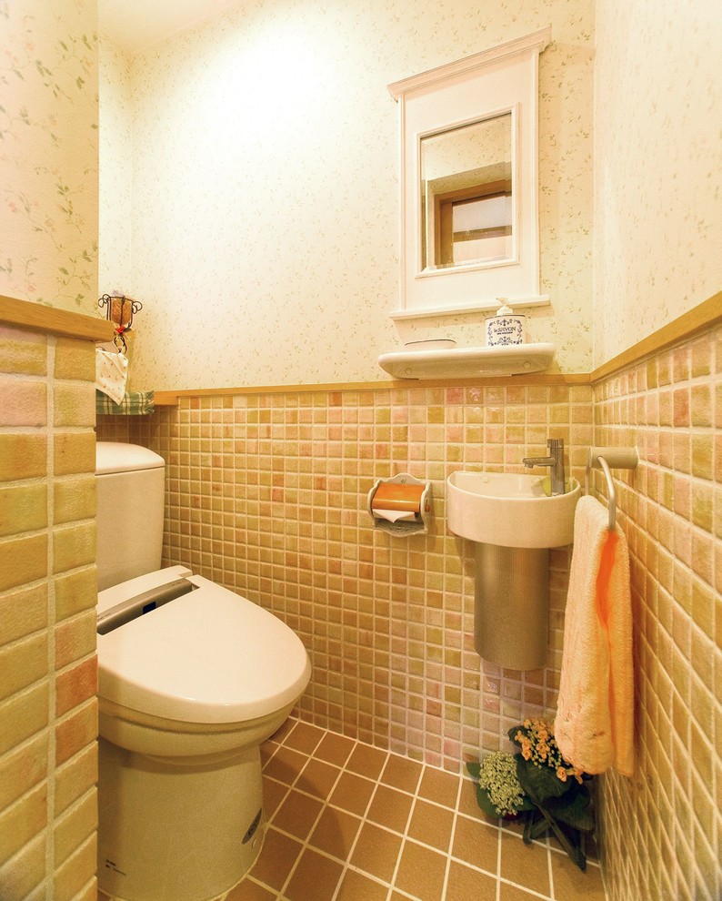 Esempio di un bagno di servizio classico con piastrelle beige, pareti beige, pavimento con piastrelle in ceramica, lavabo sospeso e pavimento marrone