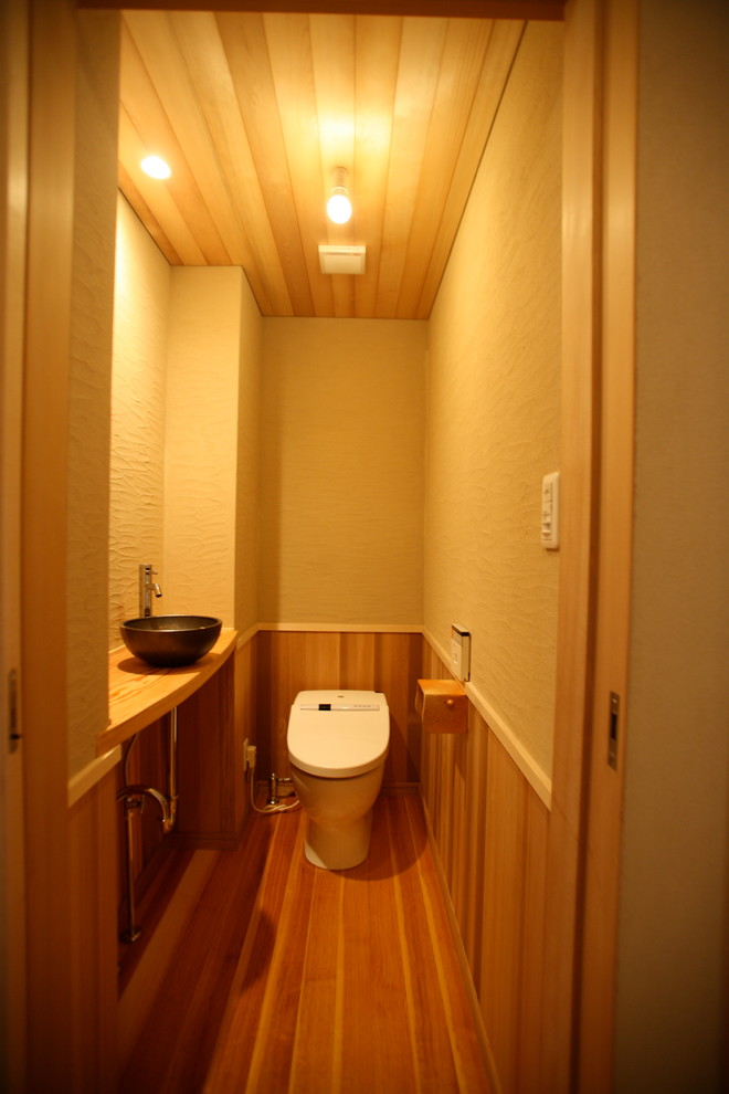 На фото: туалет среднего размера в восточном стиле с бежевыми стенами, светлым паркетным полом, накладной раковиной и бежевым полом