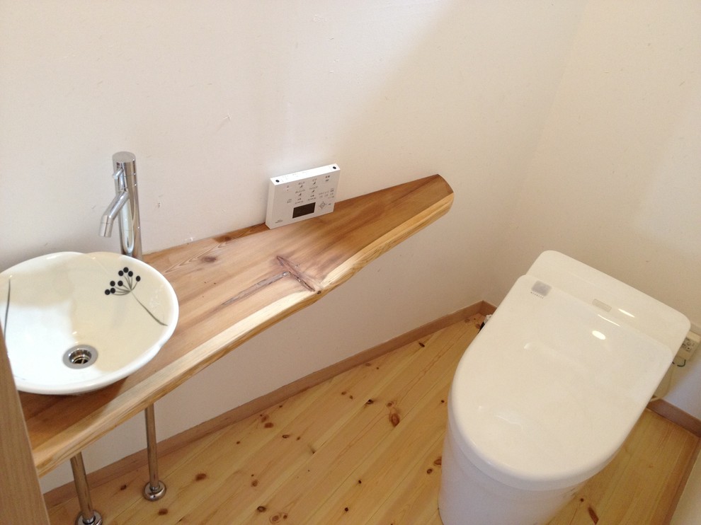 Example of a small light wood floor and beige floor powder room design in Other with white walls and a drop-in sink