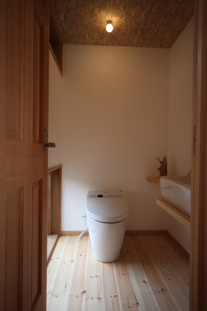 This is an example of a medium sized world-inspired cloakroom in Other with white walls, light hardwood flooring, wooden worktops, beige floors and beige worktops.