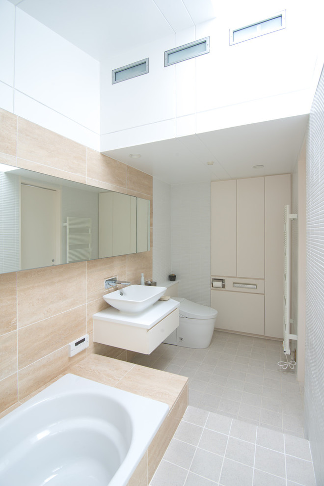 Cette photo montre un WC et toilettes scandinave avec WC à poser, un carrelage beige, du carrelage en marbre, un mur beige, un sol en carrelage de céramique, un lavabo posé et un sol gris.