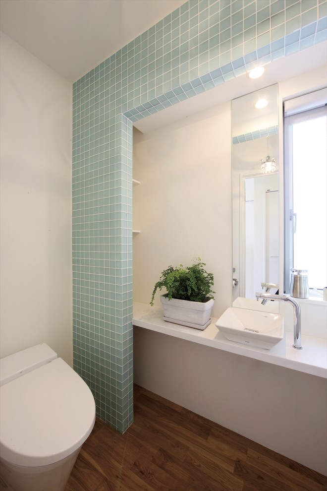 Источник вдохновения для домашнего уюта: туалет в морском стиле с унитазом-моноблоком, синей плиткой, белыми стенами, паркетным полом среднего тона и настольной раковиной