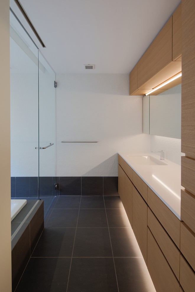Modernes Badezimmer mit flächenbündigen Schrankfronten, braunen Schränken, weißer Wandfarbe, integriertem Waschbecken und schwarzem Boden in Tokio