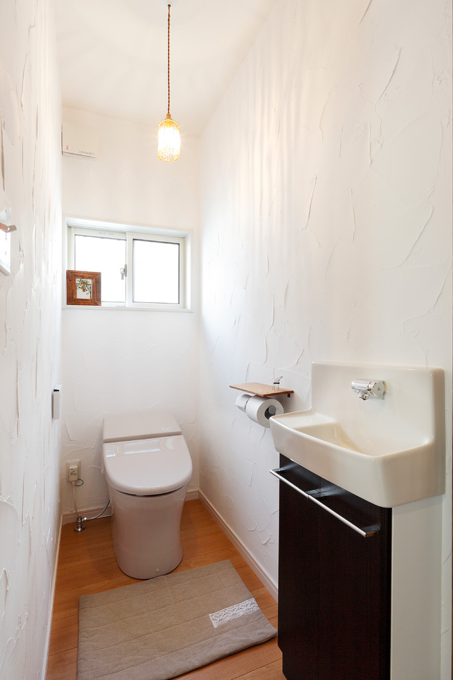 Источник вдохновения для домашнего уюта: туалет в современном стиле с плоскими фасадами, черными фасадами, белыми стенами, паркетным полом среднего тона и коричневым полом