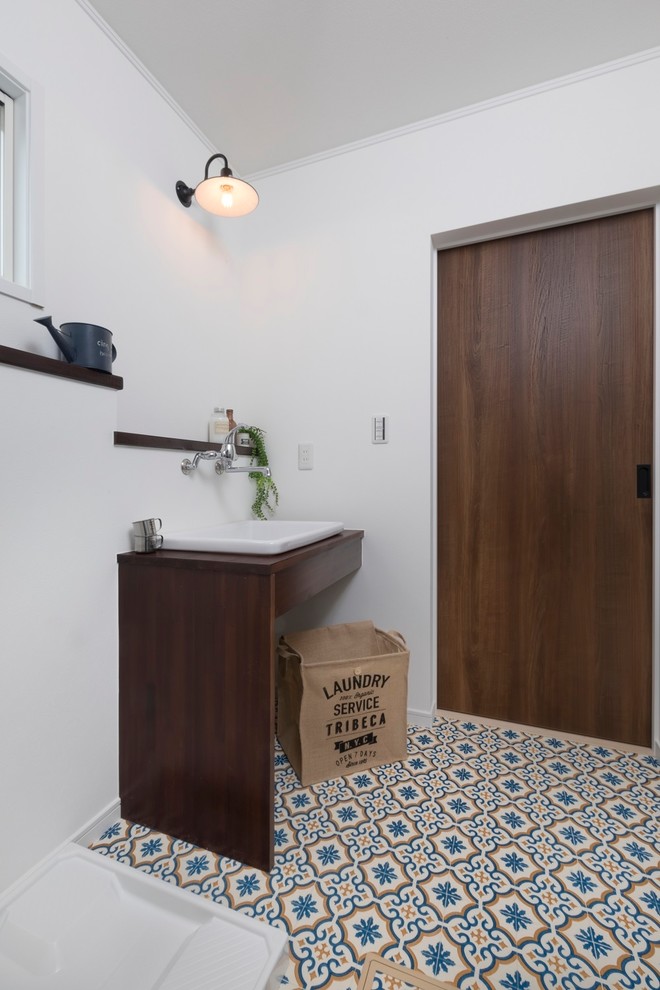Cette image montre un WC et toilettes rustique avec un placard sans porte, un carrelage blanc, un mur blanc, un sol en vinyl, une vasque, un plan de toilette en bois et un sol multicolore.