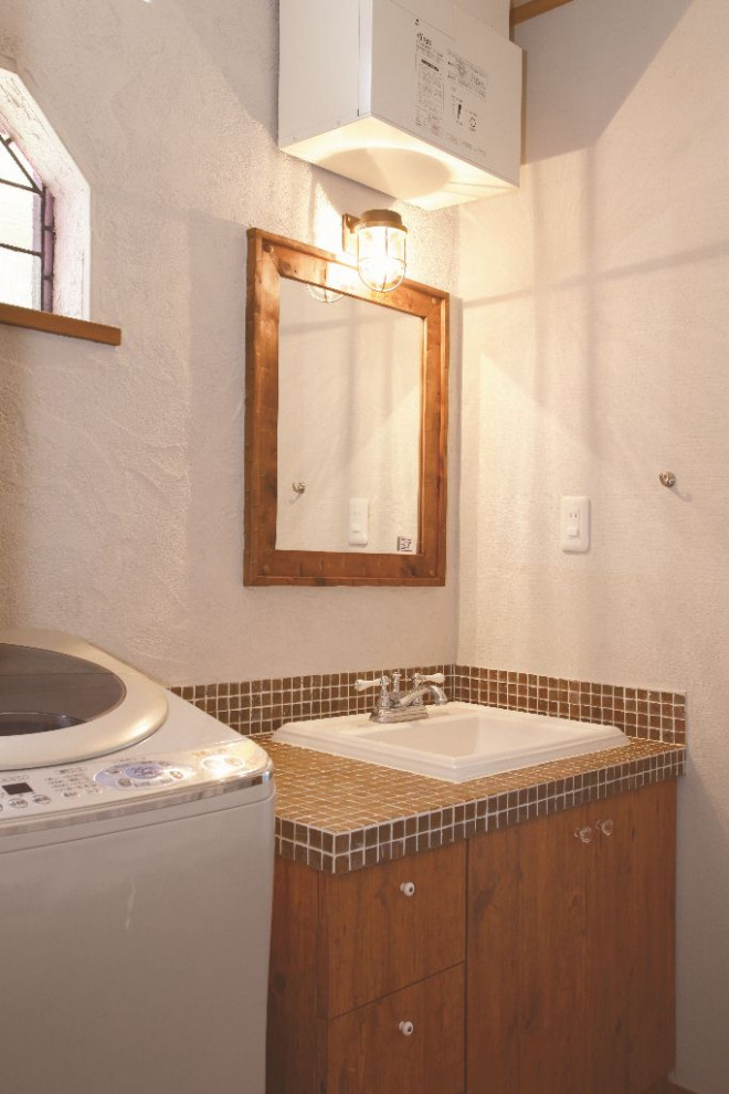 На фото: маленький туалет в стиле модернизм с плоскими фасадами, коричневыми фасадами, белой плиткой, белыми стенами, полом из керамической плитки, накладной раковиной, столешницей из плитки, коричневым полом и коричневой столешницей для на участке и в саду с
