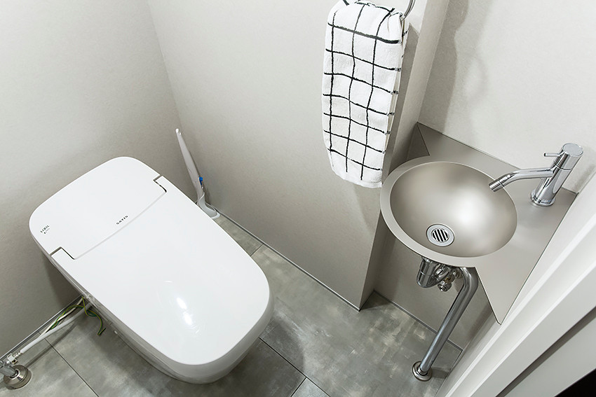 Réalisation d'un petit WC et toilettes design avec un placard sans porte, des portes de placard noires, un mur gris, un sol en vinyl, un plan de toilette en acier inoxydable, un sol gris et un plan de toilette gris.