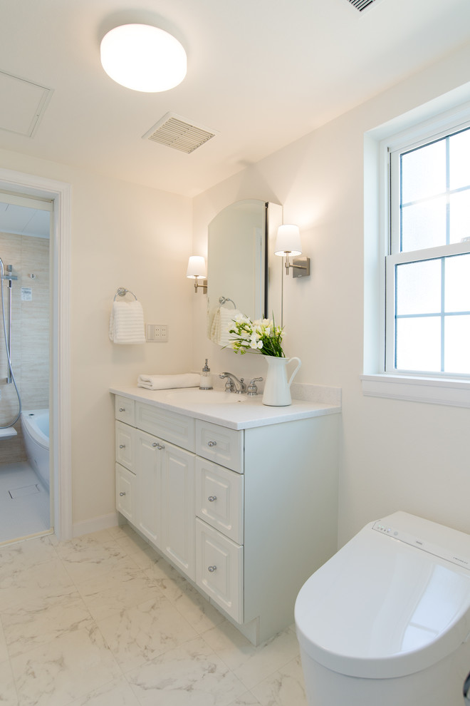 Design ideas for a large traditional cloakroom in Other with raised-panel cabinets, white cabinets, a one-piece toilet, beige tiles, limestone tiles, white walls, an integrated sink, solid surface worktops, white floors and grey worktops.