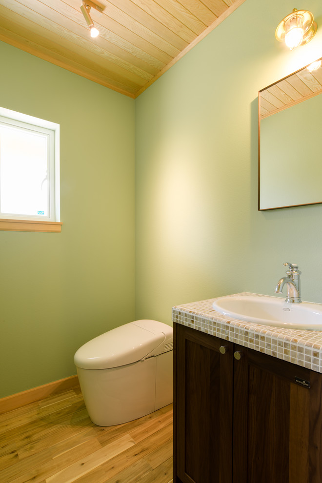 Idéer för ett mellanstort exotiskt flerfärgad toalett, med skåp i shakerstil, bruna skåp, flerfärgad kakel, gröna väggar, mellanmörkt trägolv, kaklad bänkskiva, brunt golv och ett nedsänkt handfat