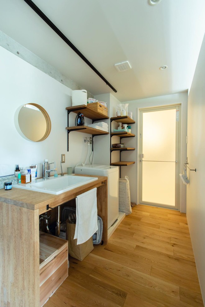 東京都下にあるインダストリアルスタイルのおしゃれなトイレ・洗面所 (白い壁、無垢フローリング、オーバーカウンターシンク、木製洗面台、茶色い床、ブラウンの洗面カウンター) の写真
