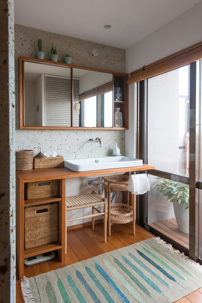 На фото: туалет в скандинавском стиле с коричневыми фасадами, разноцветными стенами, паркетным полом среднего тона, настольной раковиной, столешницей из дерева, коричневым полом и коричневой столешницей
