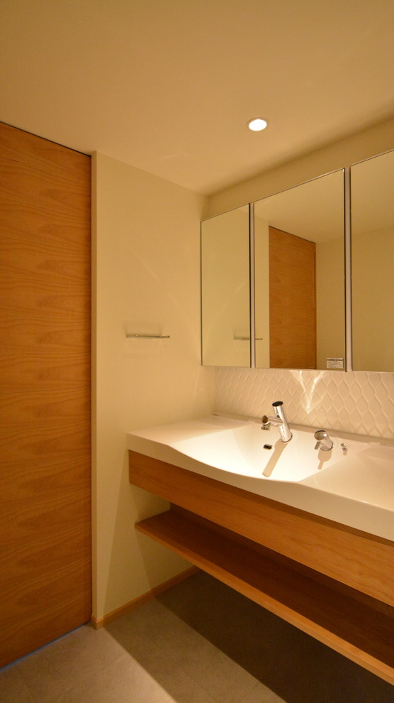 Mittelgroße Gästetoilette mit Toilette mit Aufsatzspülkasten, weißen Fliesen, weißer Wandfarbe, integriertem Waschbecken und grauem Boden in Sonstige