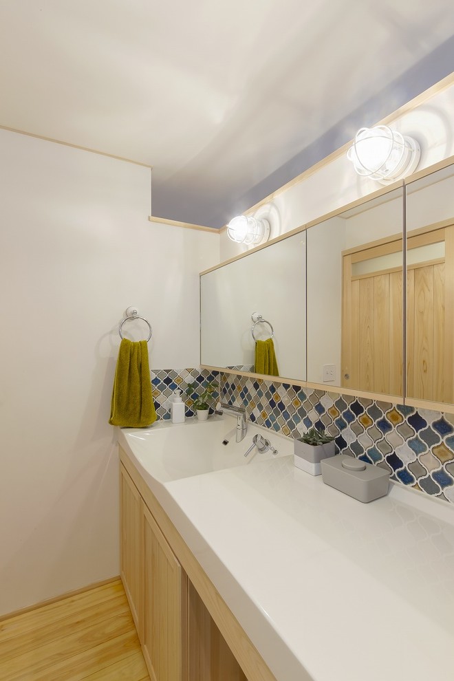 Imagen de aseo nórdico con baldosas y/o azulejos multicolor, paredes blancas, suelo de madera en tonos medios, lavabo integrado, encimera de acrílico, suelo beige y encimeras blancas