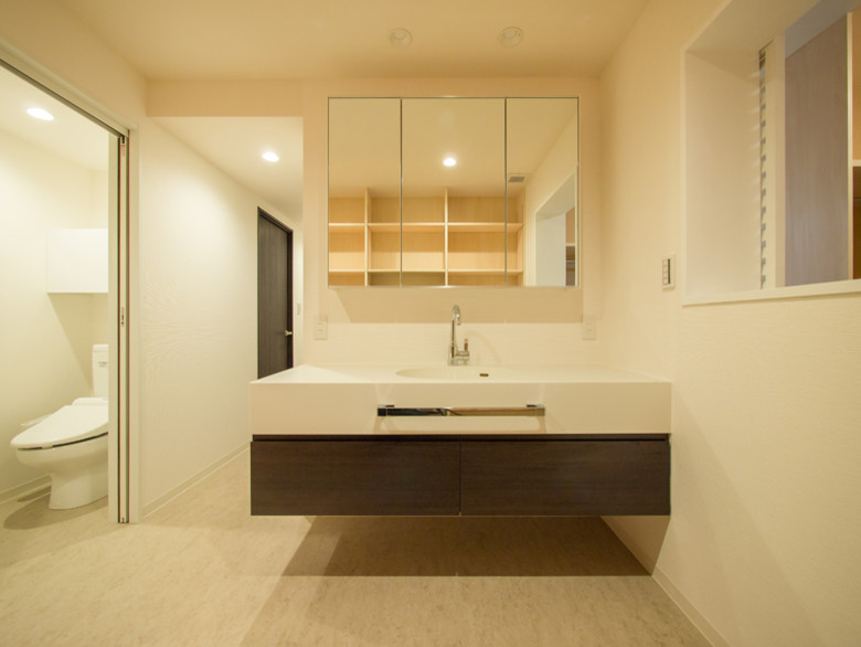 Mittelgroße Moderne Gästetoilette mit flächenbündigen Schrankfronten, dunklen Holzschränken, Toilette mit Aufsatzspülkasten, weißer Wandfarbe, Vinylboden, integriertem Waschbecken, Mineralwerkstoff-Waschtisch und weißem Boden in Tokio
