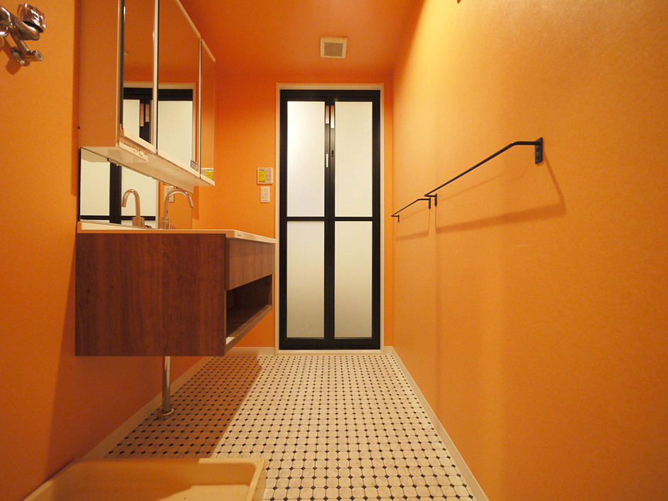 Cette image montre un WC et toilettes méditerranéen en bois brun avec un mur orange, un sol en vinyl, un lavabo intégré, un sol blanc et un plan de toilette blanc.